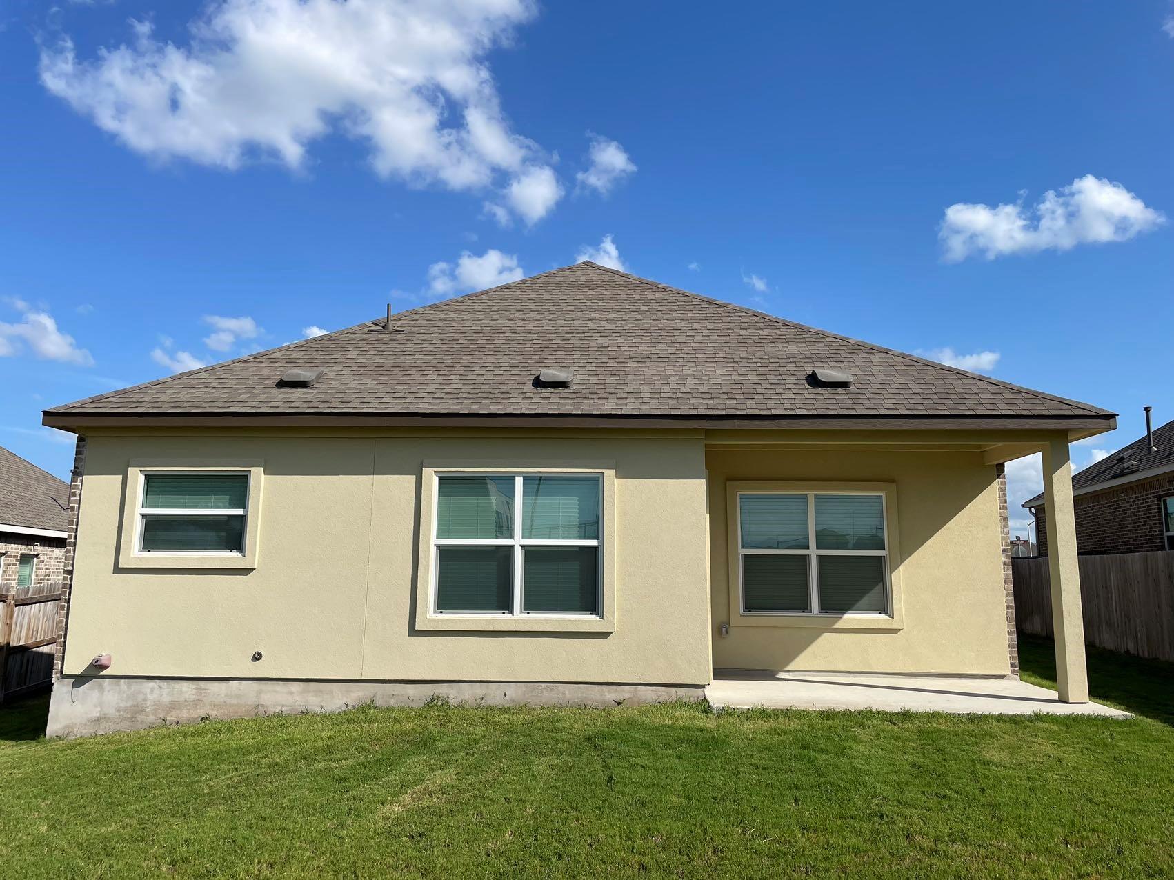 1625 Woolsey Way Leander, TX 78641 - Photo 15 of 17 The property features an exterior with a light-colored stucco finish, a brown shingle roof, and a grassy lawn