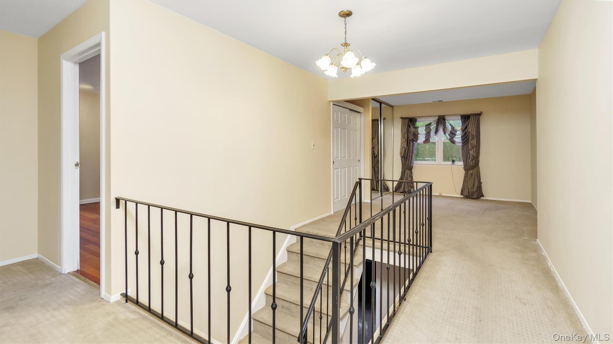 47 Carriage Road Roslyn, NY 11576 - Photo 18 of 31 Hallway featuring baseboards, light carpet, an upstairs landing, and a chandelier