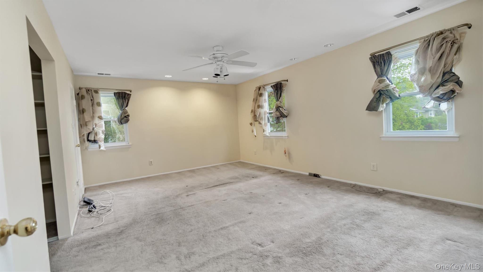 47 Carriage Road Roslyn, NY 11576 - Photo 19 of 31 Empty room with ceiling fan, carpet flooring, and a healthy amount of sunlight