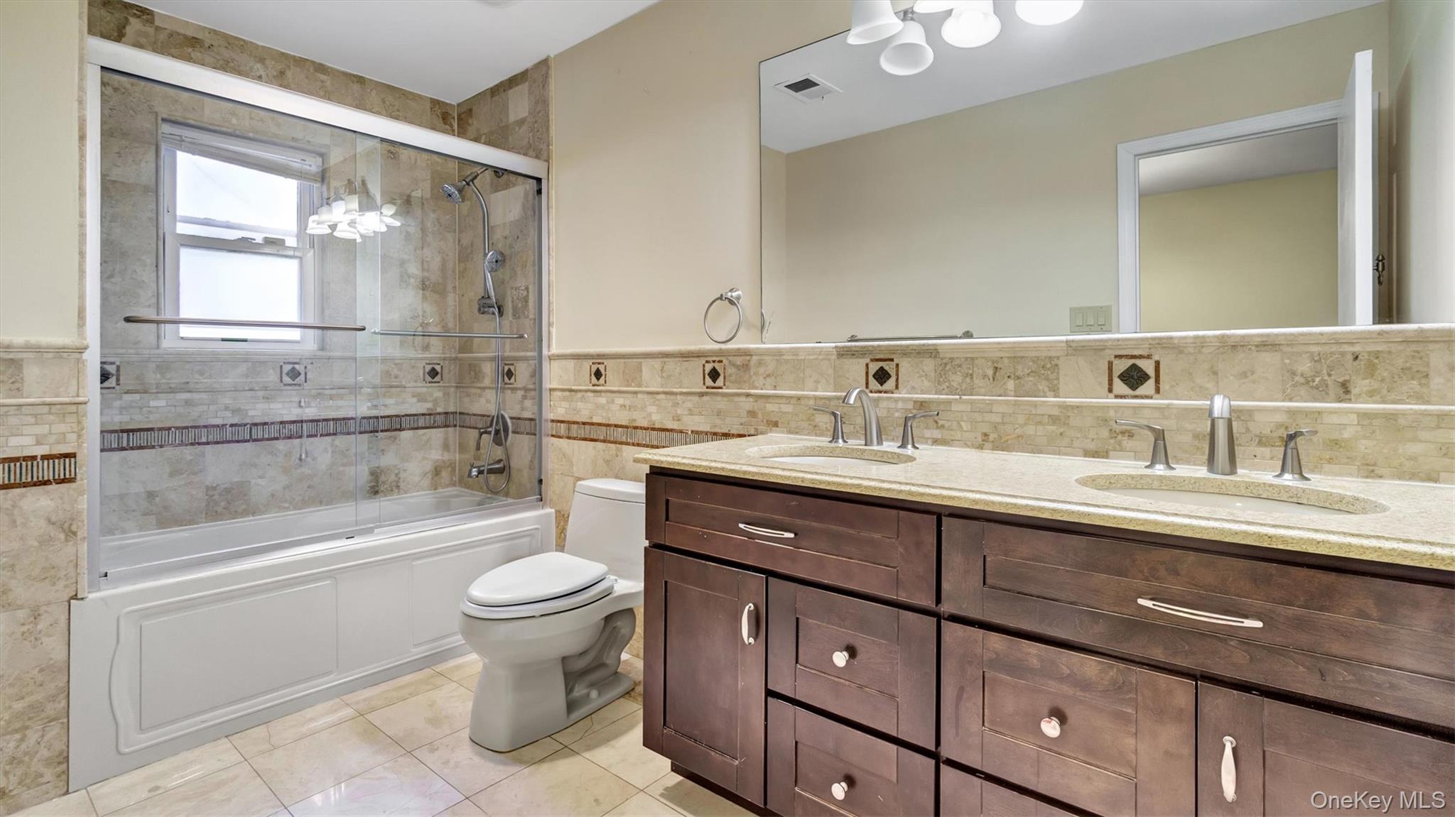 47 Carriage Road Roslyn, NY 11576 - Photo 26 of 31 Full bathroom featuring toilet, a sink, tile walls, visible vents, and tile patterned flooring