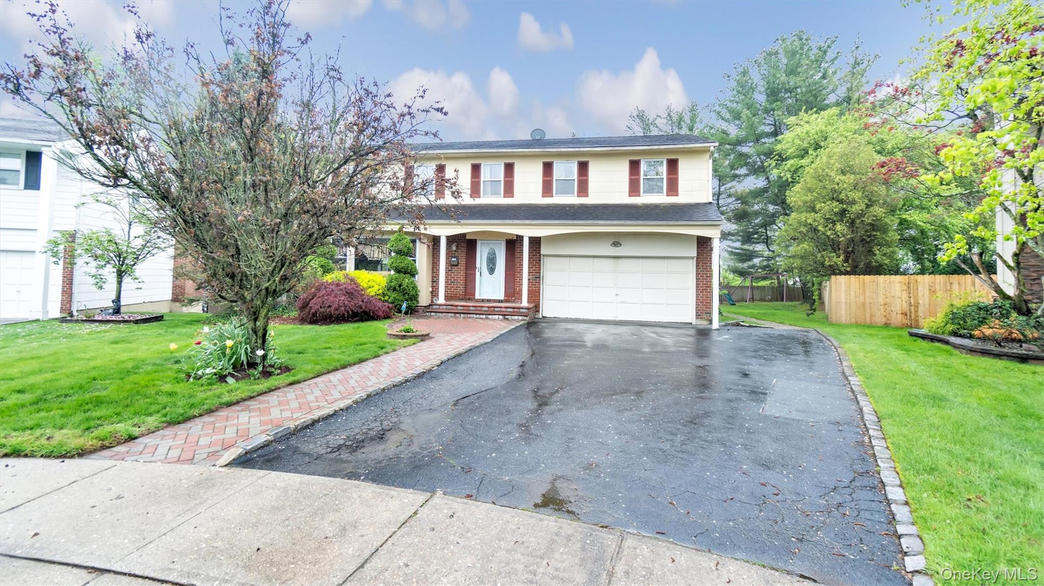 47 Carriage Road Roslyn, NY 11576 - Photo 3 of 31 Traditional-style home featuring a garage, fence, aphalt driveway, a front yard, and brick siding