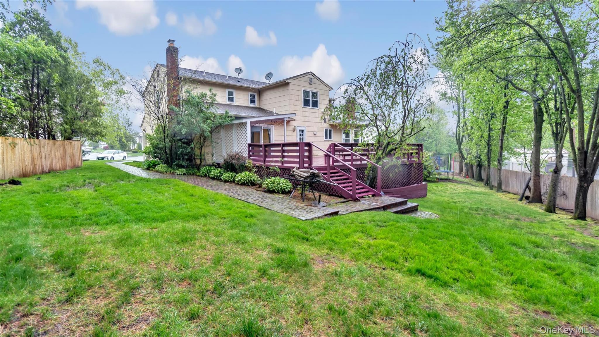 47 Carriage Road Roslyn, NY 11576 - Photo 31 of 31 Rear view of house with a lawn, fence, a chimney, and a deck