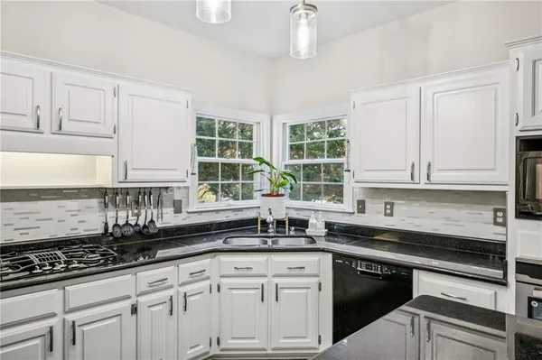 a kitchen with granite countertop a sink stainless steel appliances and white cabinets