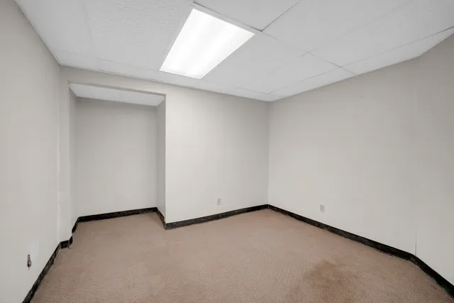 a view of an empty room with wooden floor and windows