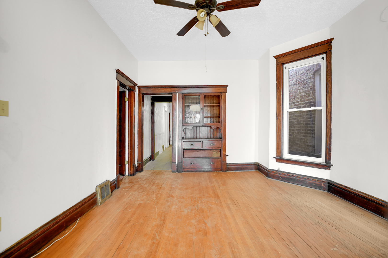6045 South Peoria Street Chicago, IL 60621 - Photo 8 of 25 a view of an empty room with a window and wooden floor