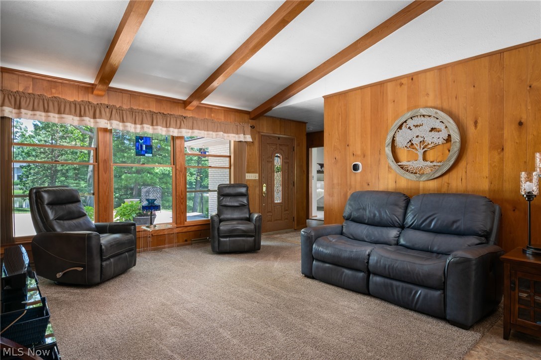 685 Sunnyside Road Vermilion, OH 44089 - Photo 12 of 50 Light-filled living space featuring wood paneling, exposed wood beams, and large picture windows