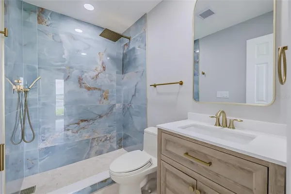 a bathroom with a shower sink vanity mirror and toilet