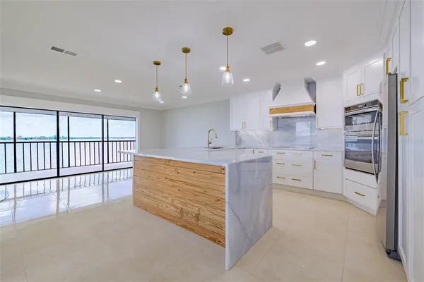 a large kitchen with stainless steel appliances kitchen island large windows and a chandelier