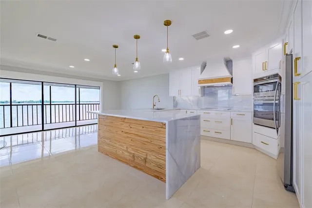 a large kitchen with stainless steel appliances kitchen island large windows and a chandelier