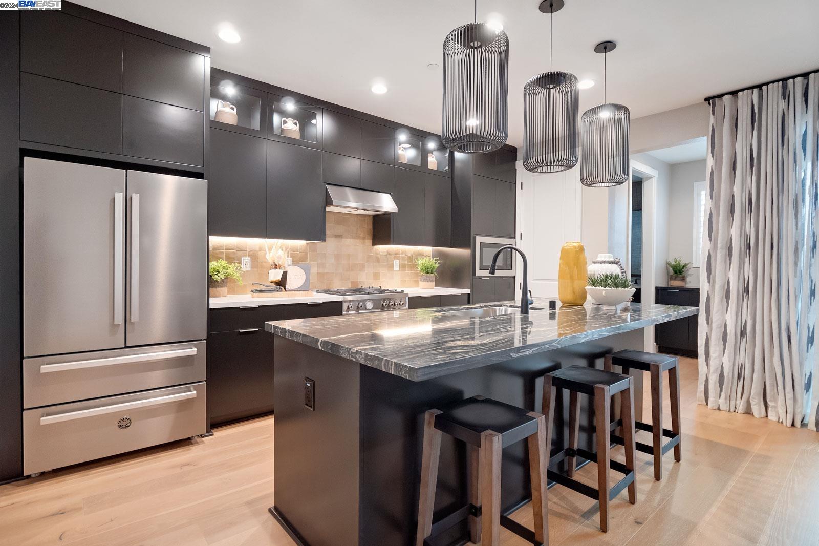 a kitchen with stainless steel appliances kitchen island granite countertop a refrigerator a sink dishwasher a stove and a dining table with wooden floor