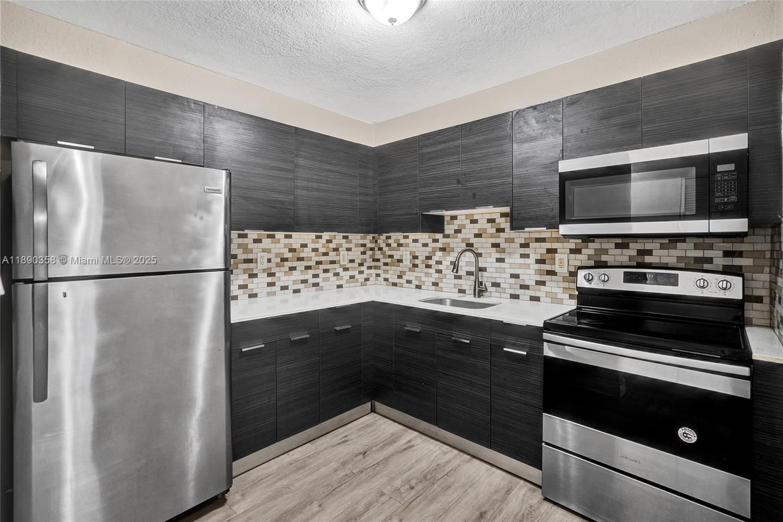 2731 Northwest 1st Street, Unit 3 Pompano Beach, FL 33069 - Photo 11 of 20 a kitchen with wooden cabinets and stainless steel appliances