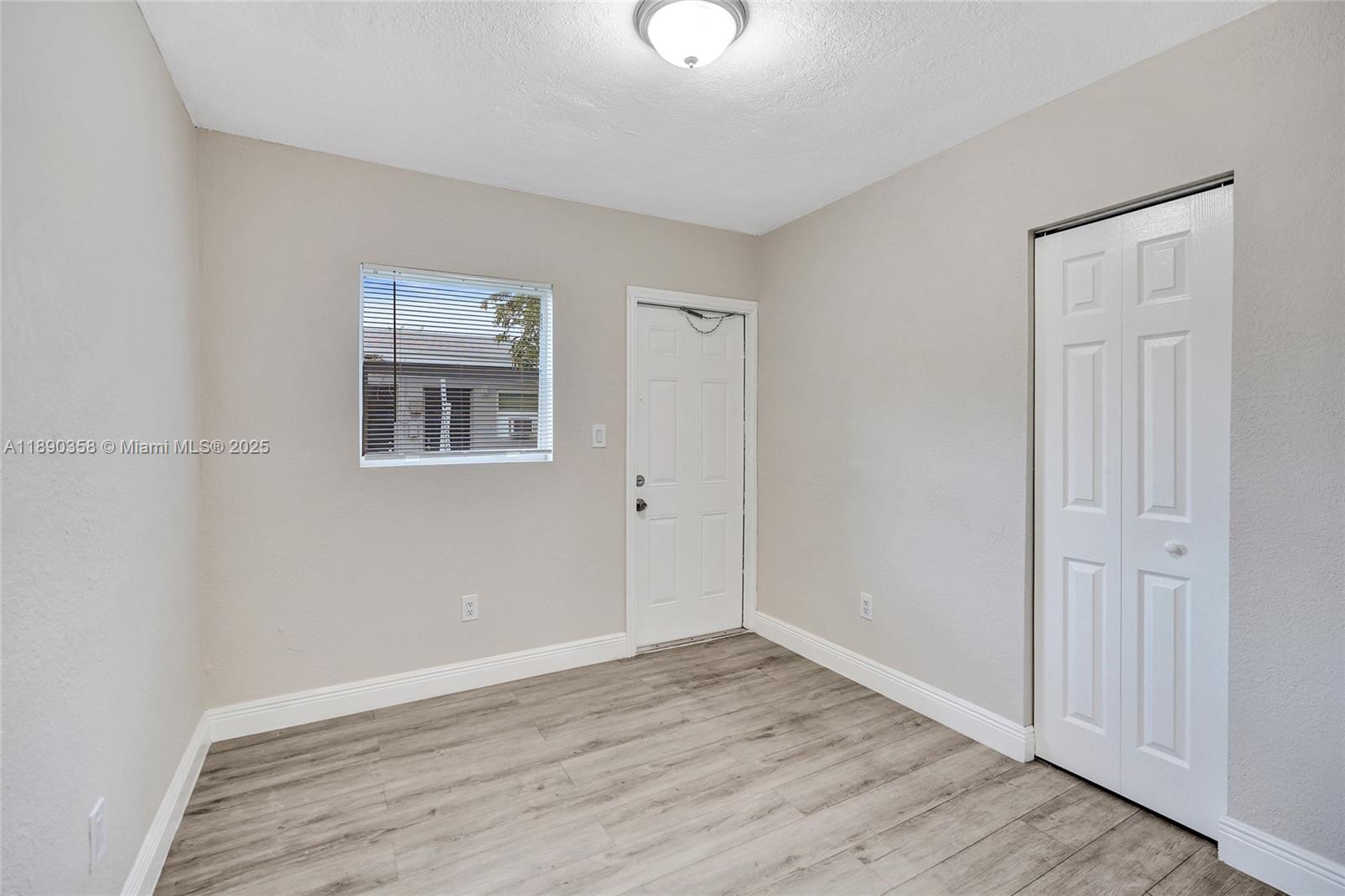 2731 Northwest 1st Street, Unit 3 Pompano Beach, FL 33069 - Photo 16 of 20 a view of an empty room with wooden floor and a window