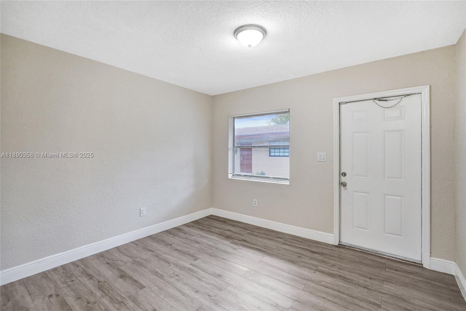 2731 Northwest 1st Street, Unit 3 Pompano Beach, FL 33069 - Photo 8 of 20 an empty room with wooden floor and windows