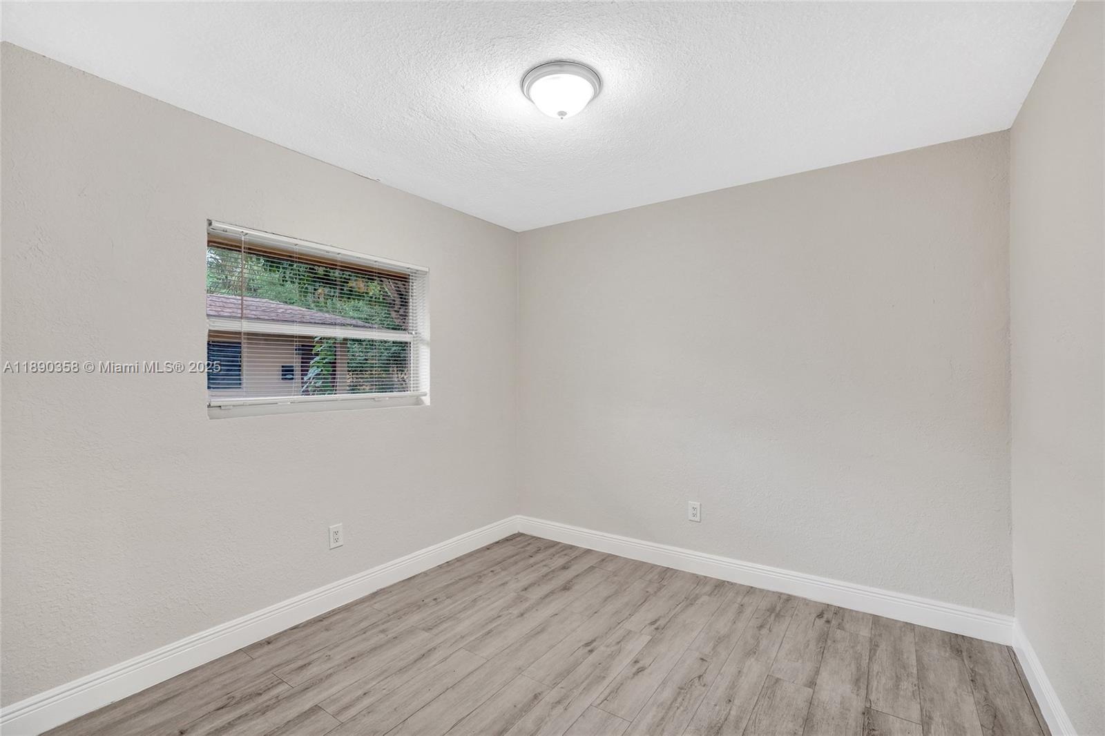 2731 Northwest 1st Street, Unit 3 Pompano Beach, FL 33069 - Photo 9 of 20 a view of an empty room with wooden floor and a window