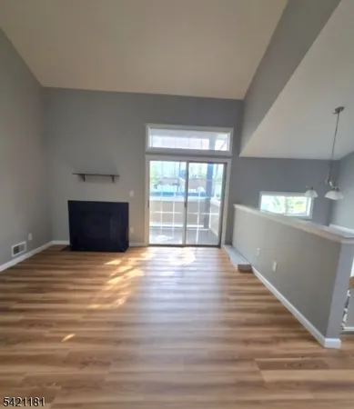 a view of empty room with wooden floor and fireplace