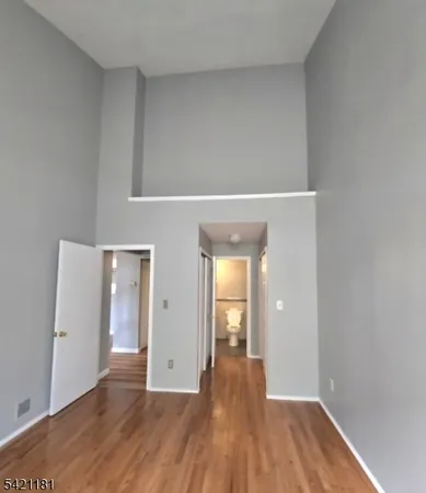 a view of an empty room with wooden floor and closet