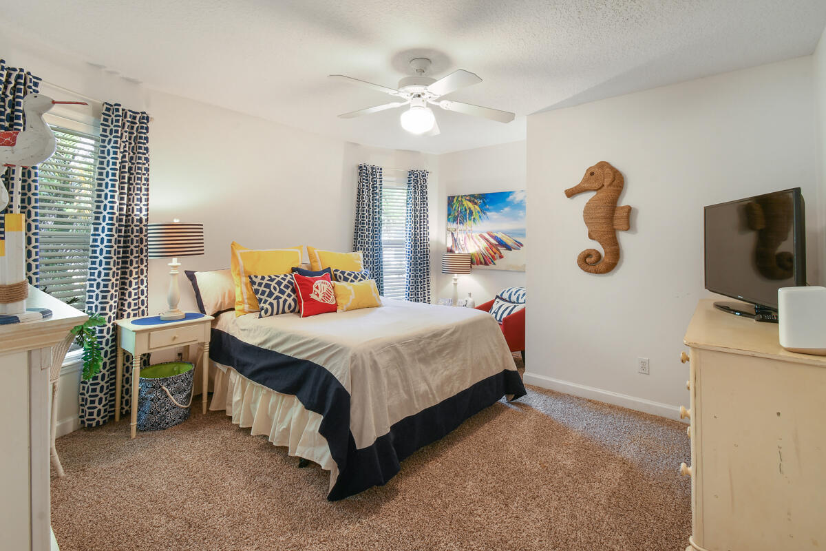 7831 Southeast Windjammer Way Hobe Sound, FL 33455 - Photo 34 of 80 a spacious bedroom with a bed and a flat screen tv