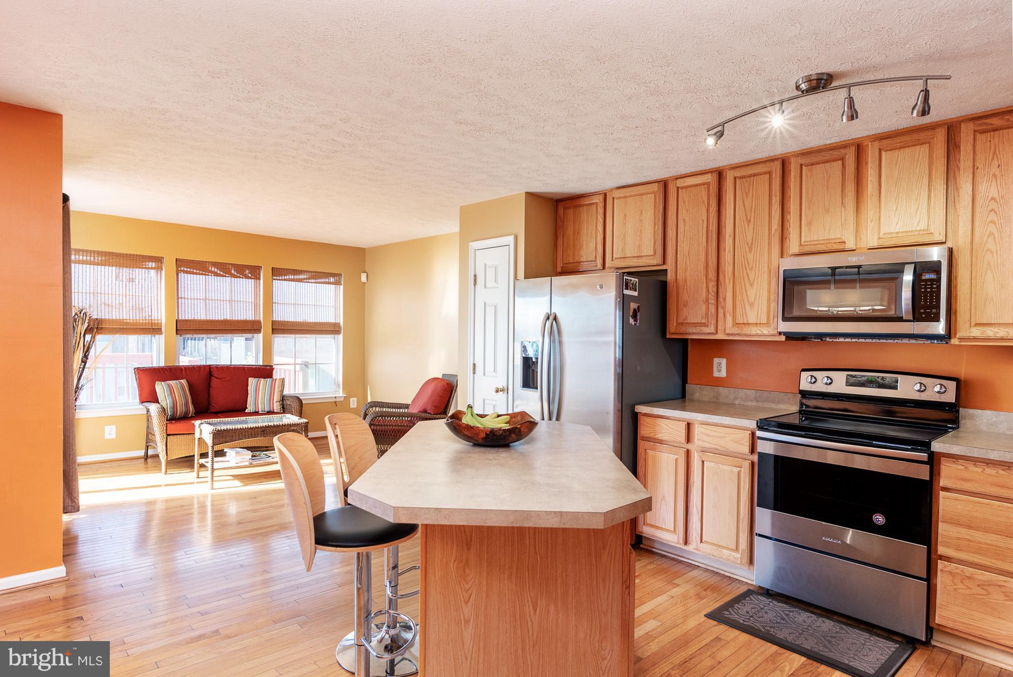802 Tipton Road Middle River, MD 21220 - Photo 5 of 30 a kitchen with stainless steel appliances a stove a sink a microwave a dining table and chairs with wooden floor