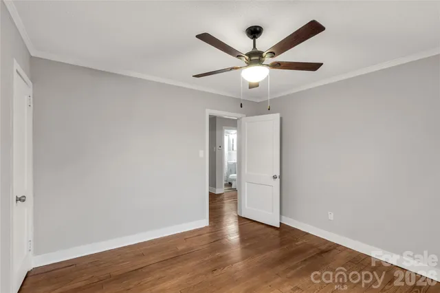 an empty room with wooden floor and a ceiling fan