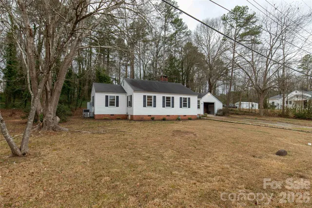 a front view of a house with a dirt yard and trees