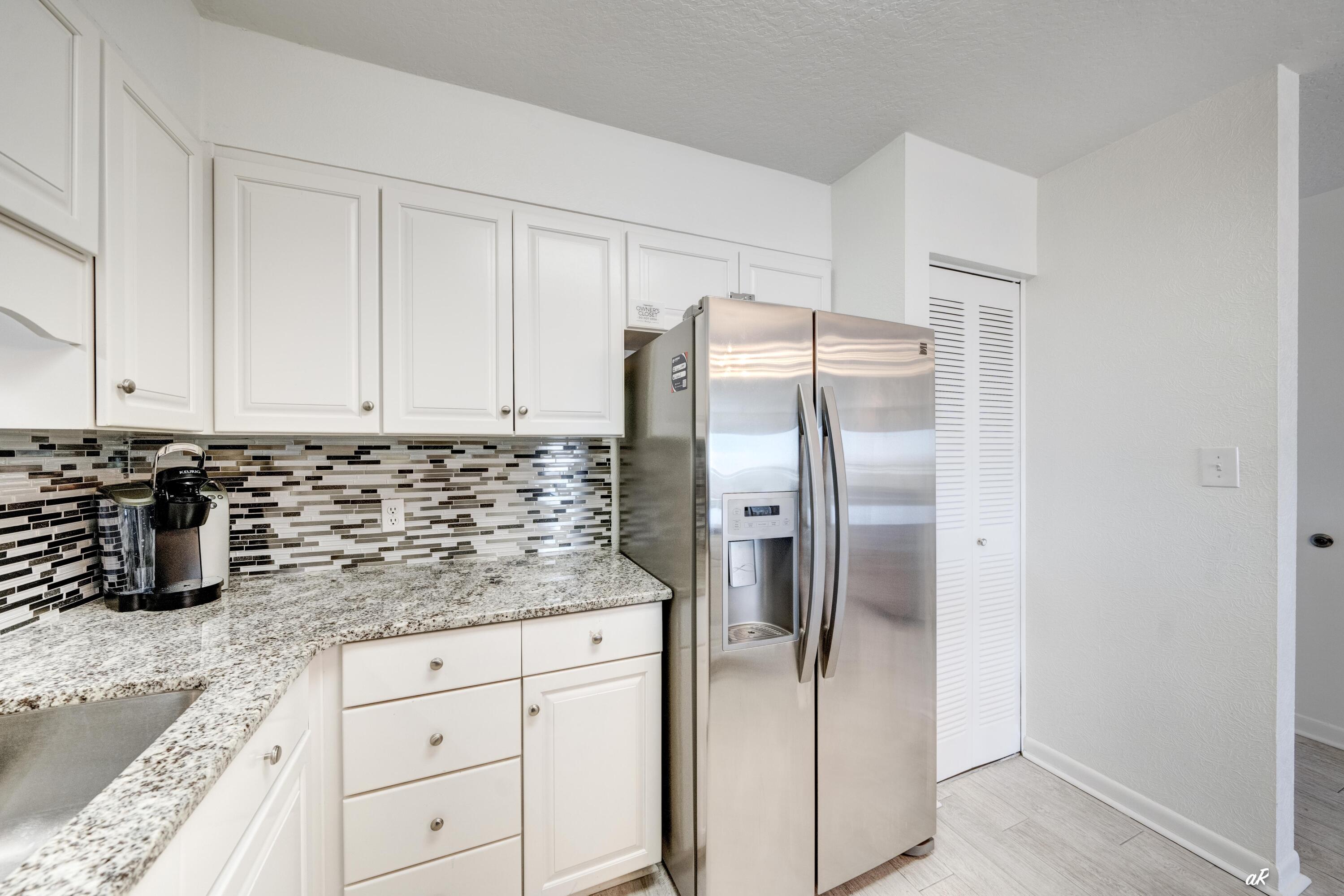 30 Moreno Point Road, Unit 404A Destin, FL 32541 - Photo 5 of 52 a kitchen with granite countertop a refrigerator sink and cabinets