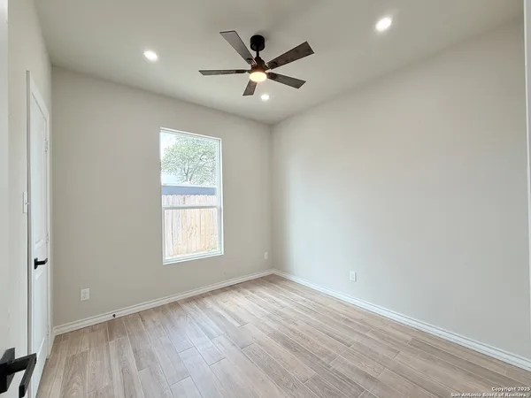 an empty room with wooden floor and windows