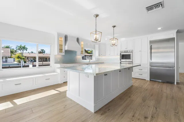 a kitchen with kitchen island granite countertop a refrigerator and a sink