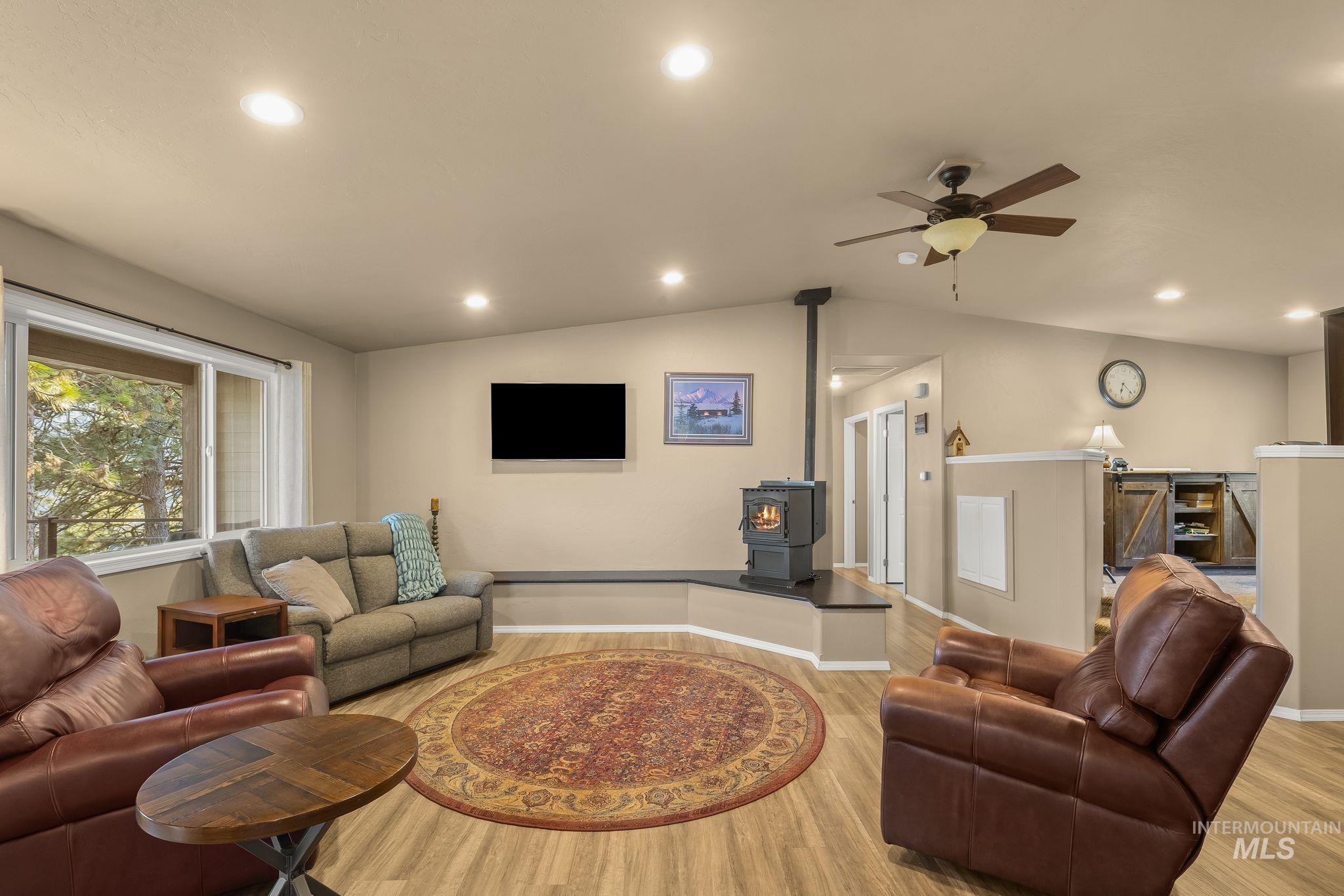 435 River Pointe Lane Lenore, ID 83541 - Photo 16 of 50 Vaulted ceiling living area featuring recessed lighting, wood-finish flooring, and a central wood-burning stove on a raised hearth