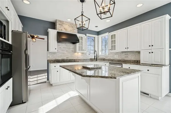 a kitchen with stainless steel appliances granite countertop a sink a stove and a refrigerator