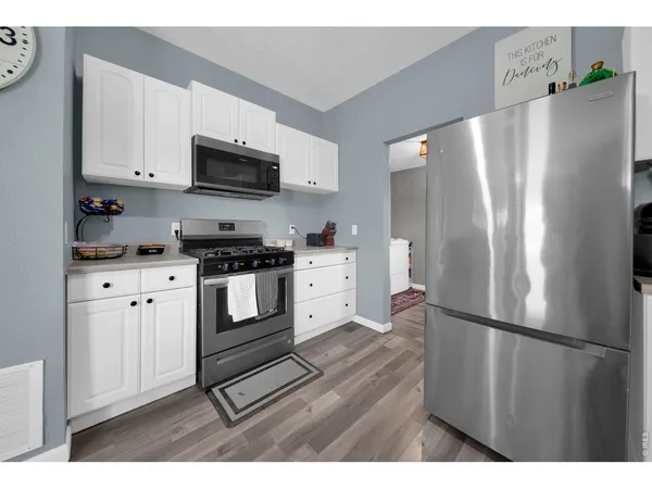 a kitchen with stainless steel appliances white cabinets and wooden floor