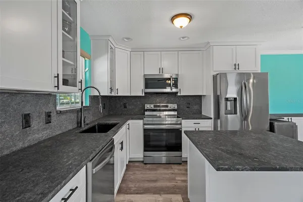 a kitchen with stainless steel appliances a microwave sink stove refrigerator and cabinets