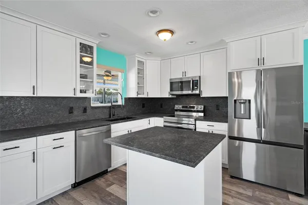 a kitchen with stainless steel appliances granite countertop a stove a sink and a microwave