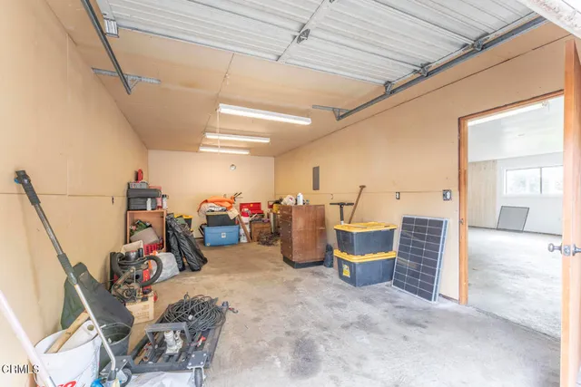 an empty room with chandelier fan and windows