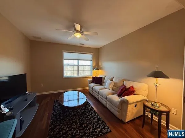 a living room with stainless steel appliances wooden floor and a window