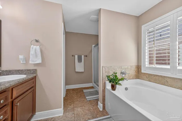 a bathroom with a granite countertop tub a sink a potted plant and a window