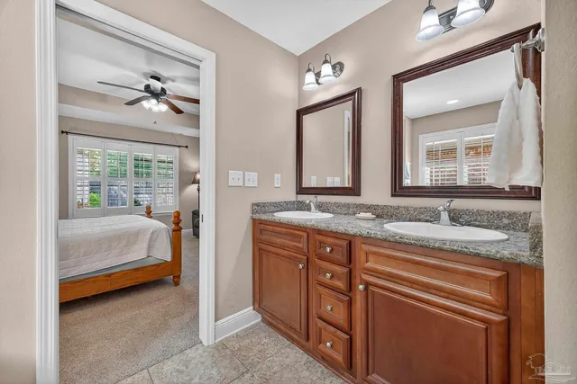 a en suite bathroom with a granite countertop sink and a large mirror