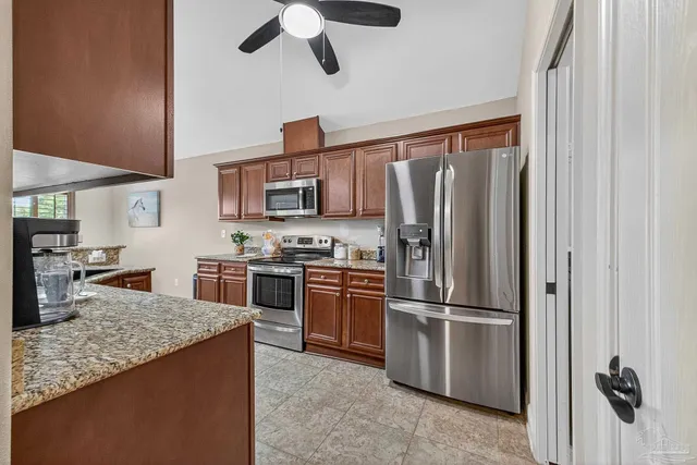 a kitchen with stainless steel appliances granite countertop a refrigerator a stove and a sink with wooden floor