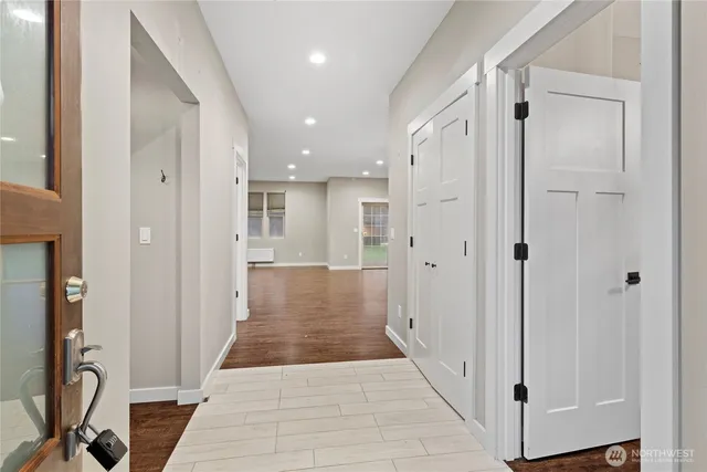 a view of a hallway with wooden floor and a bathroom