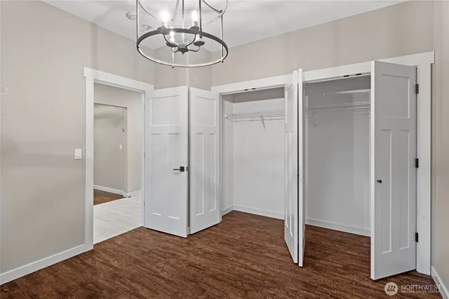a view of an empty room with wooden floor and closet area