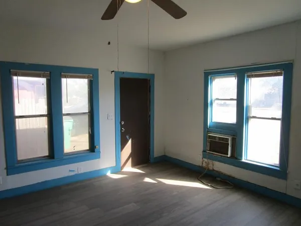 an empty room with ceiling fan and windows