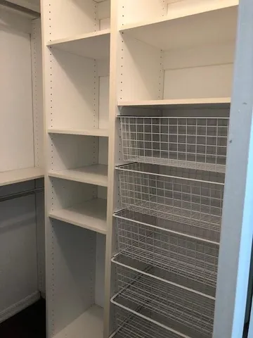 an empty room with wooden floor closet and windows