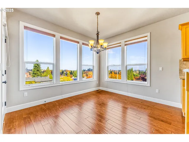 a view of an empty room with window and wooden floor