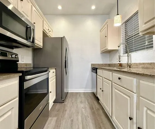 a kitchen with stainless steel appliances granite countertop a stove a sink and a microwave