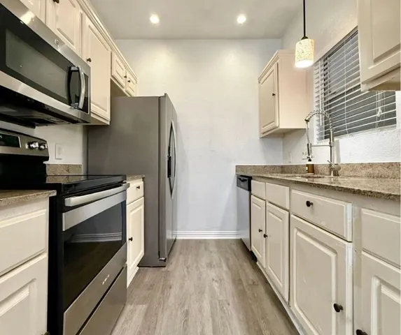 a kitchen with stainless steel appliances granite countertop a stove a sink and a microwave