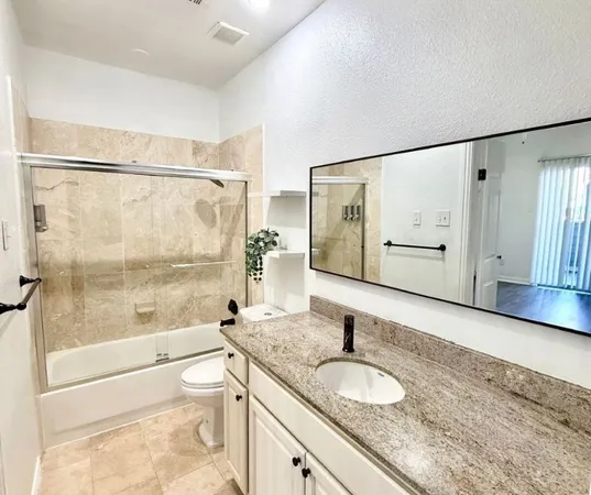 a bathroom with a granite countertop sink toilet and shower
