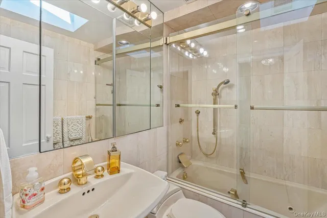 a bathroom with a tub shower sink and mirror