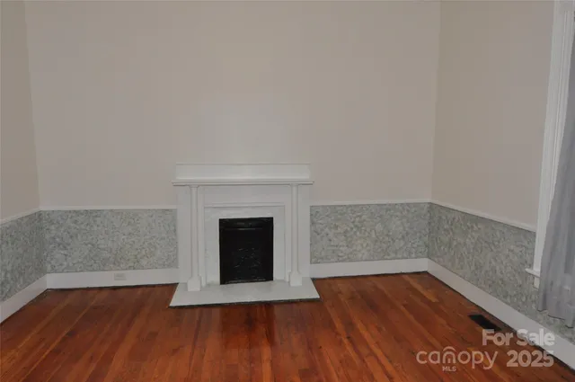 a view of empty room with wooden floor and fireplace