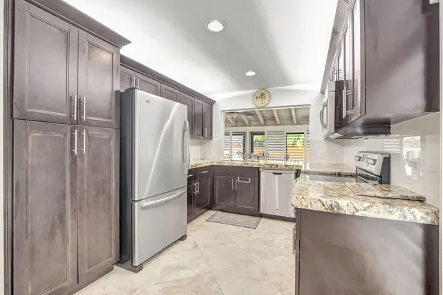 a kitchen with stainless steel appliances granite countertop a refrigerator and a sink