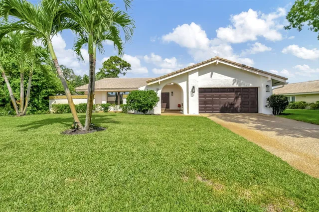 a view of house with a big yard and potted plants