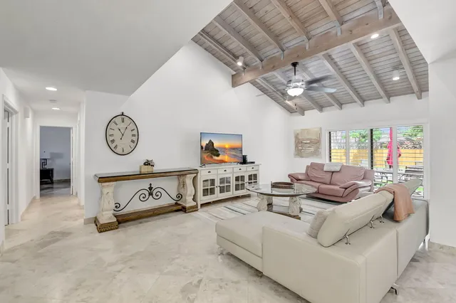 a living room with furniture a clock and a ceiling fan
